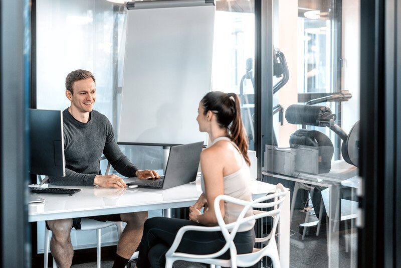 Trainer sitzt am Tisch mit einer Kundin